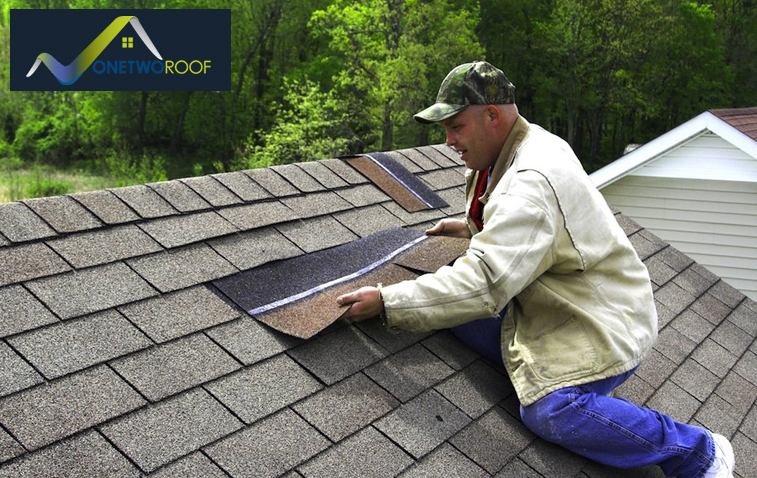 Roofer replacing damaged shingles on asphalt roof